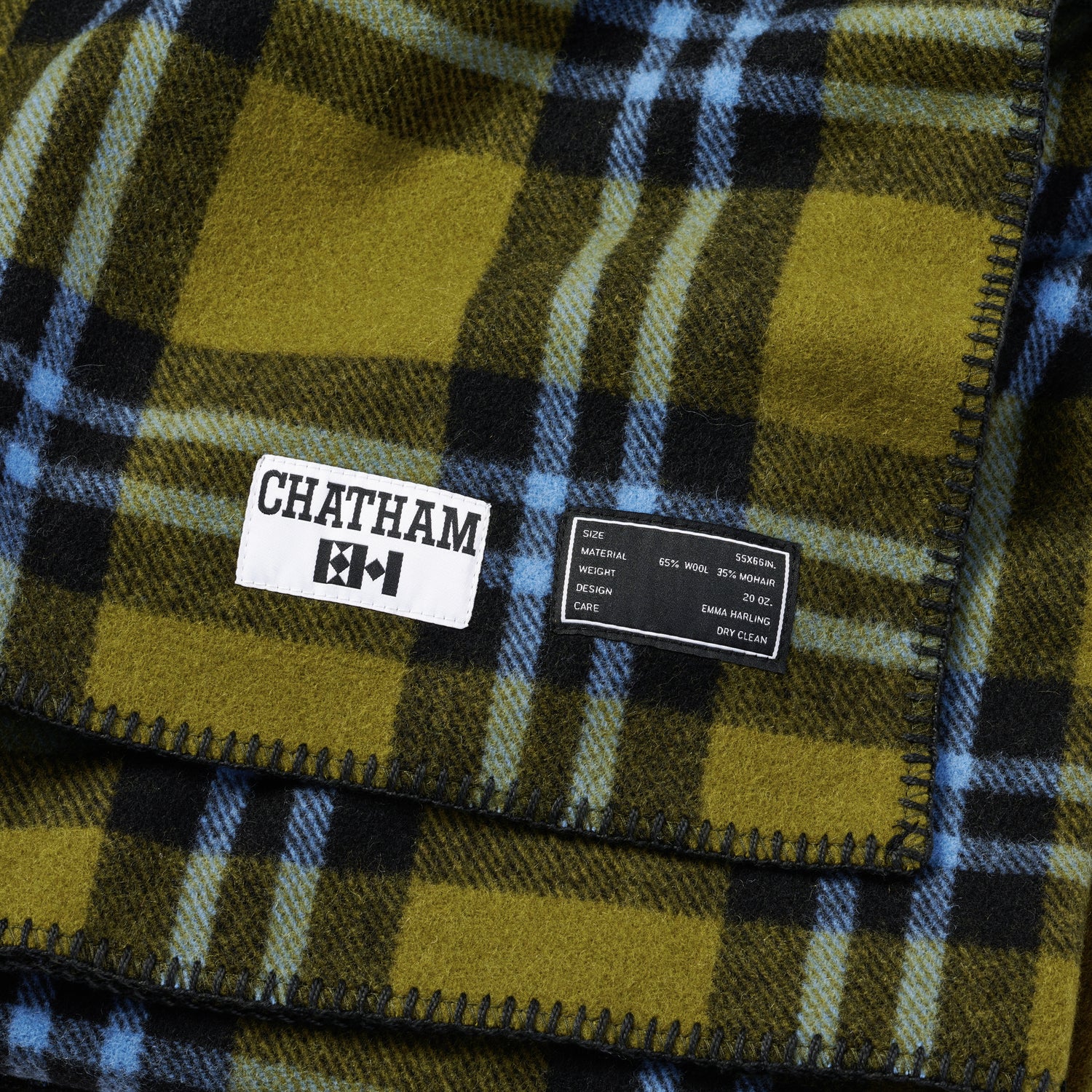 A green wool blanket with black and blue plaid. Closeup showing details of the label which says "Chatham".